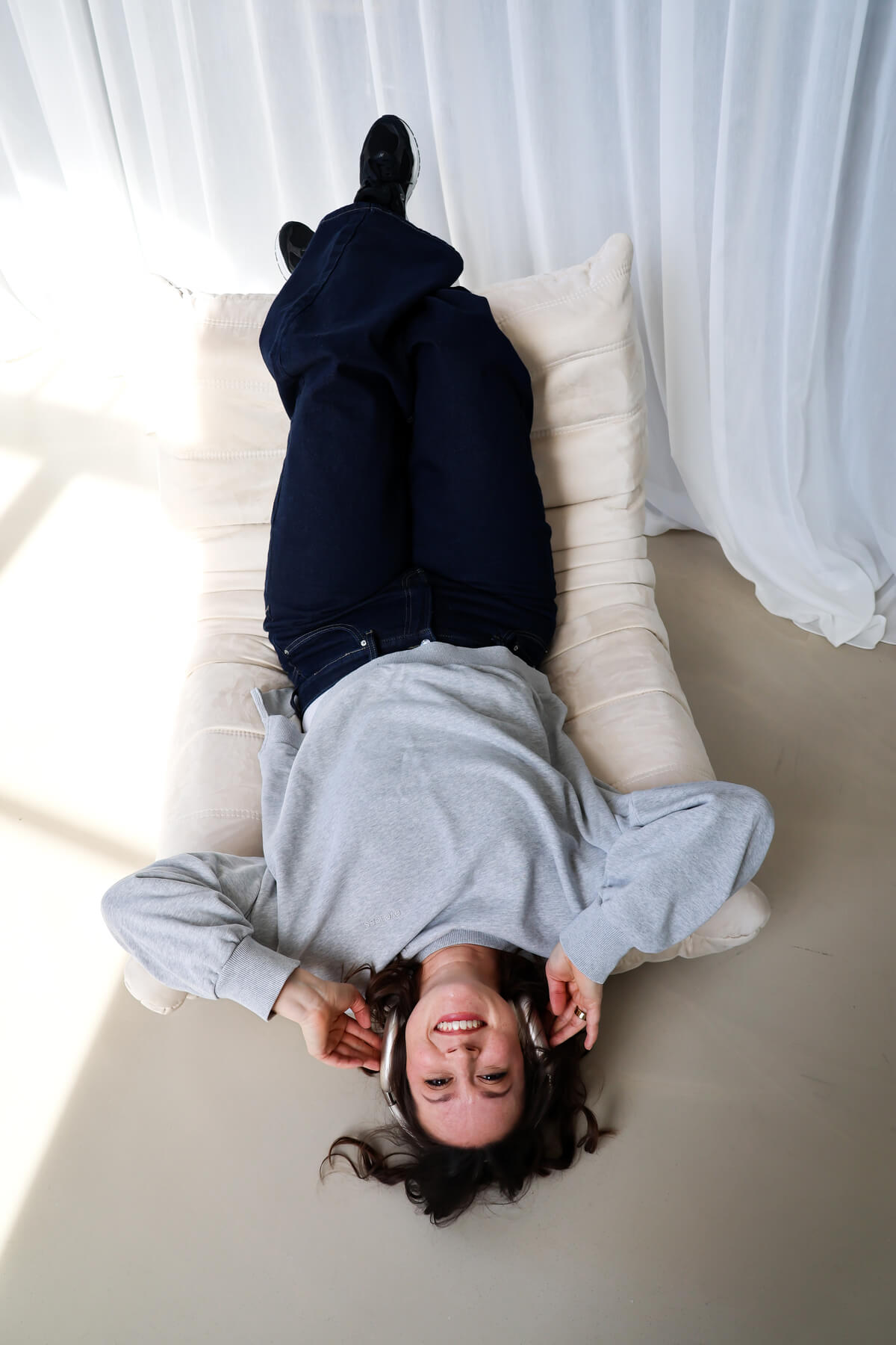 Steph liegt kopfüber auf Bodensessel und hat Kopfhörer auf den Ohren | Steph Reinhardt